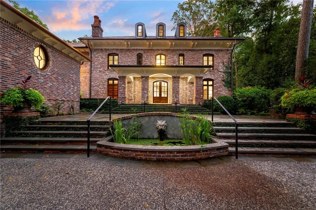 Brick exterior architecture with a columned porch entrance, dormer windows, and a circular window accent