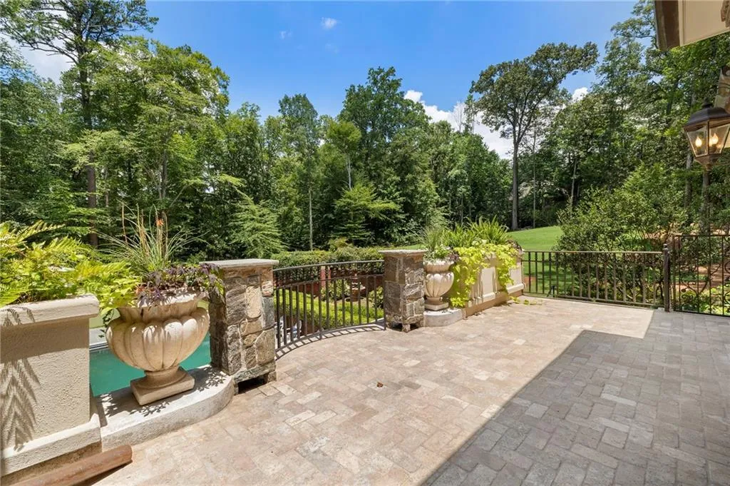 Expansive paver patio with stone pillars and decorative wrought iron railing