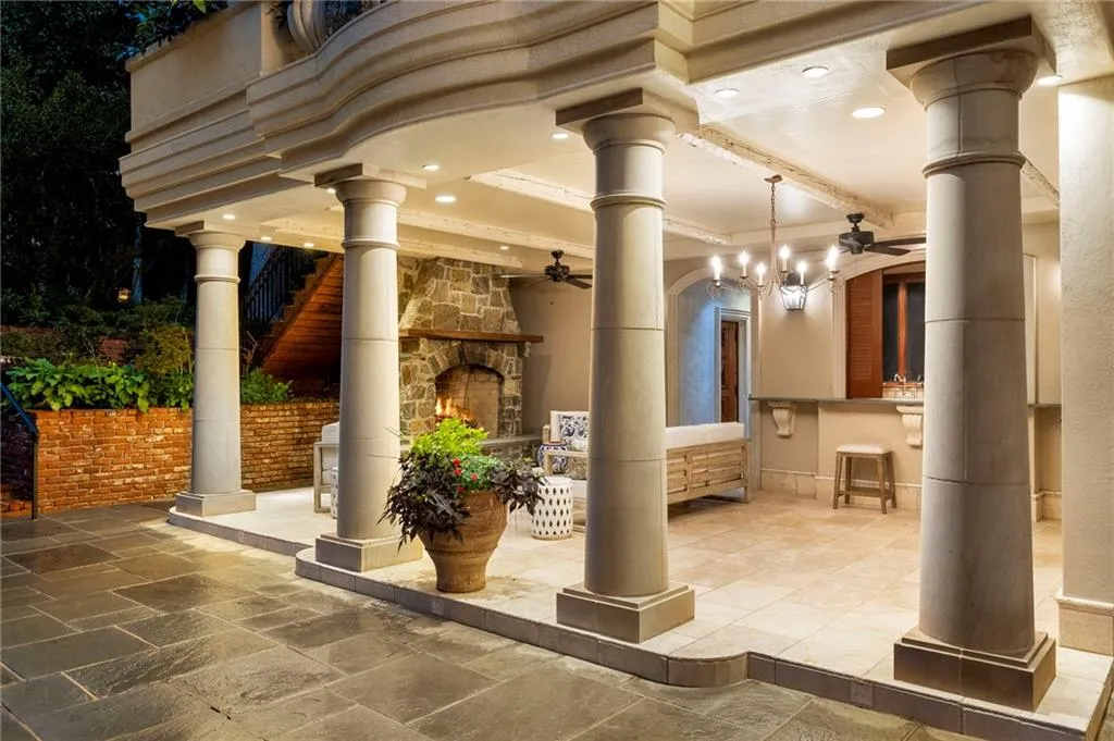 Covered patio featuring classical columns, stone fireplace, recessed lighting, ceiling fans, and a built-in bar