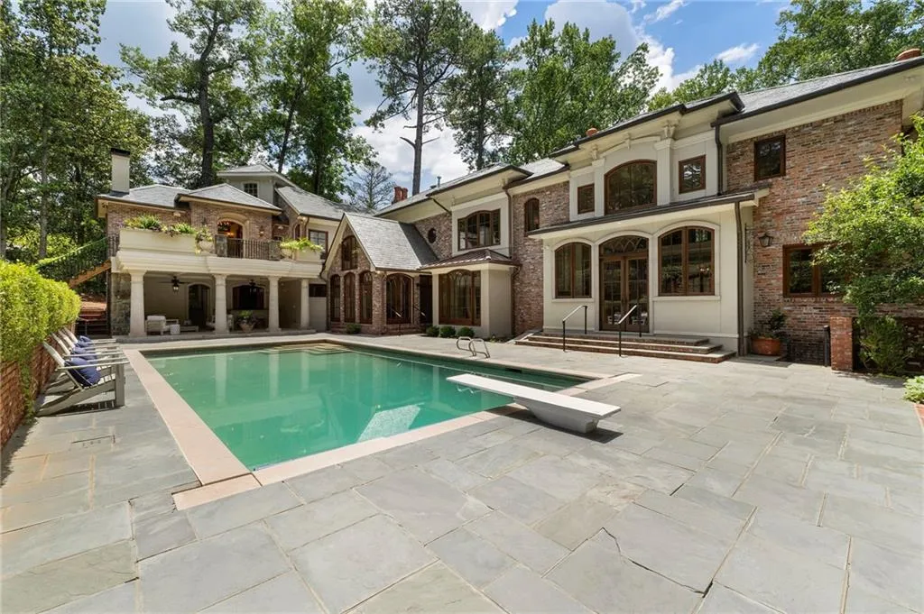 Expansive paver patio surrounding a rectangular swimming pool with a diving board