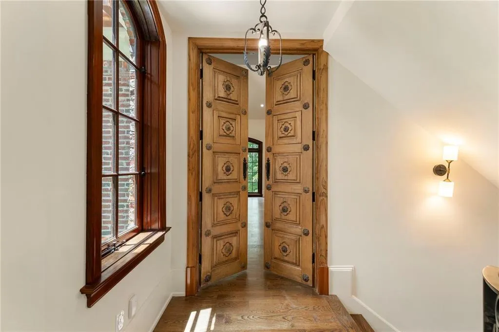 Entryway featuring ornate double doors with decorative hardware, rich wood-finish flooring, and a dark iron chandelier
