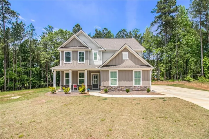 Two-story residence featuring a combination of horizontal and vertical siding, a covered front porch with white columns, and a stone facade detail