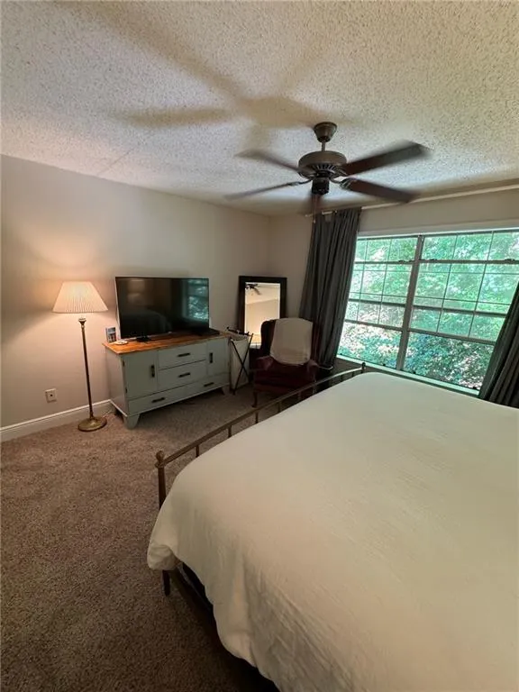 Carpeted bedroom with ceiling fan and a textured ceiling