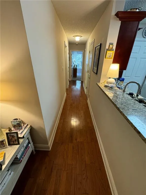 Hall with a textured ceiling and dark hardwood / wood-style flooring