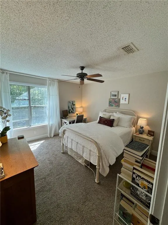 Bedroom featuring ceiling fan, dark carpet, and a textured ceiling