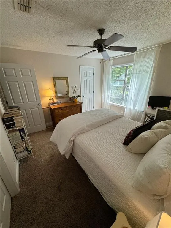 Bedroom with ceiling fan, carpet floors, and a textured ceiling