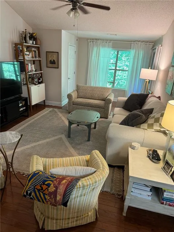 Living room with ceiling fan, a textured ceiling, and hardwood / wood-style floors
