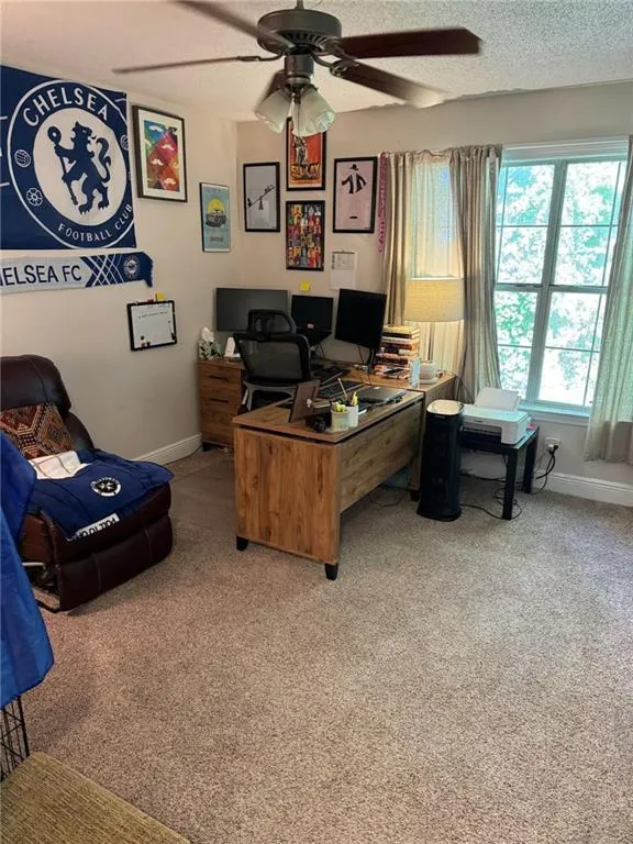 Carpeted office space featuring a textured ceiling and ceiling fan