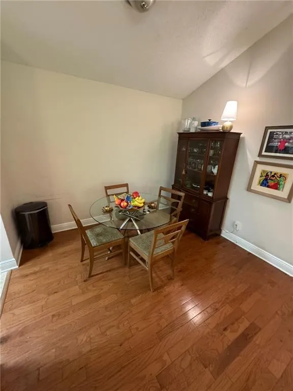 Dining space featuring vaulted ceiling and hardwood / wood-style floors