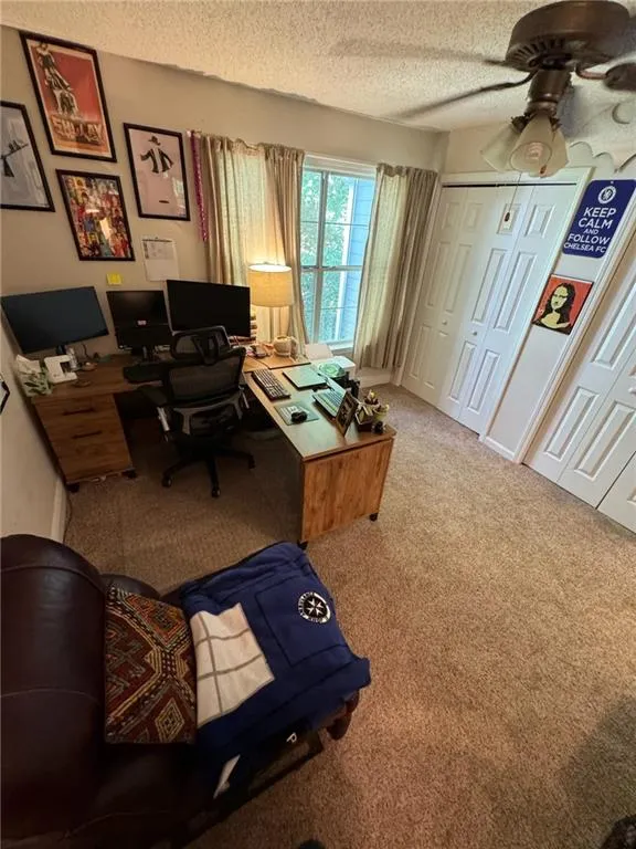 Carpeted office with a textured ceiling and ceiling fan