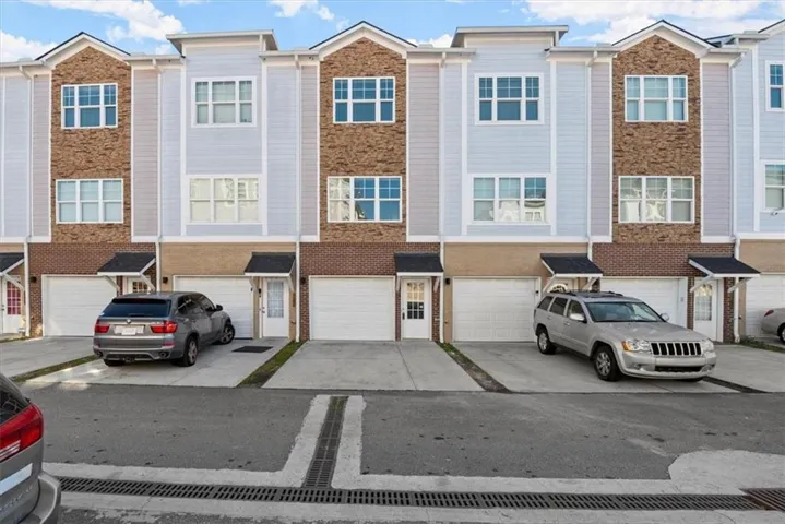 Townhome exterior featuring brick and siding facade, individual garages, and covered entryways