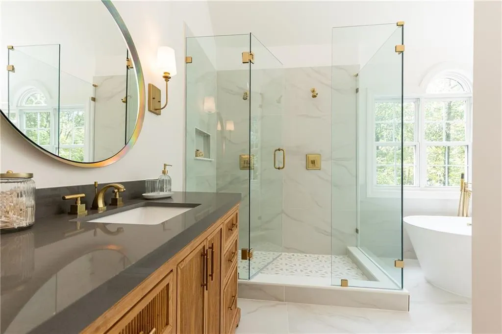 Shower has dual showerheads and seamless glass doors