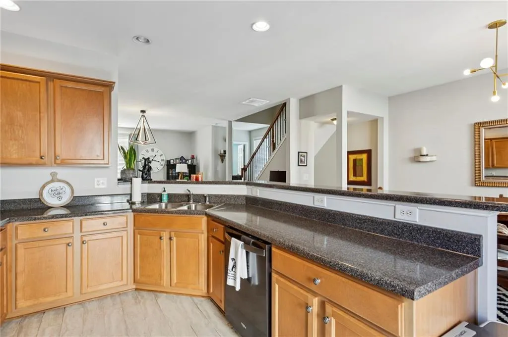 Kitchen featuring pendant lighting, stainless steel dishwasher, brown cabinets, and recessed lighting