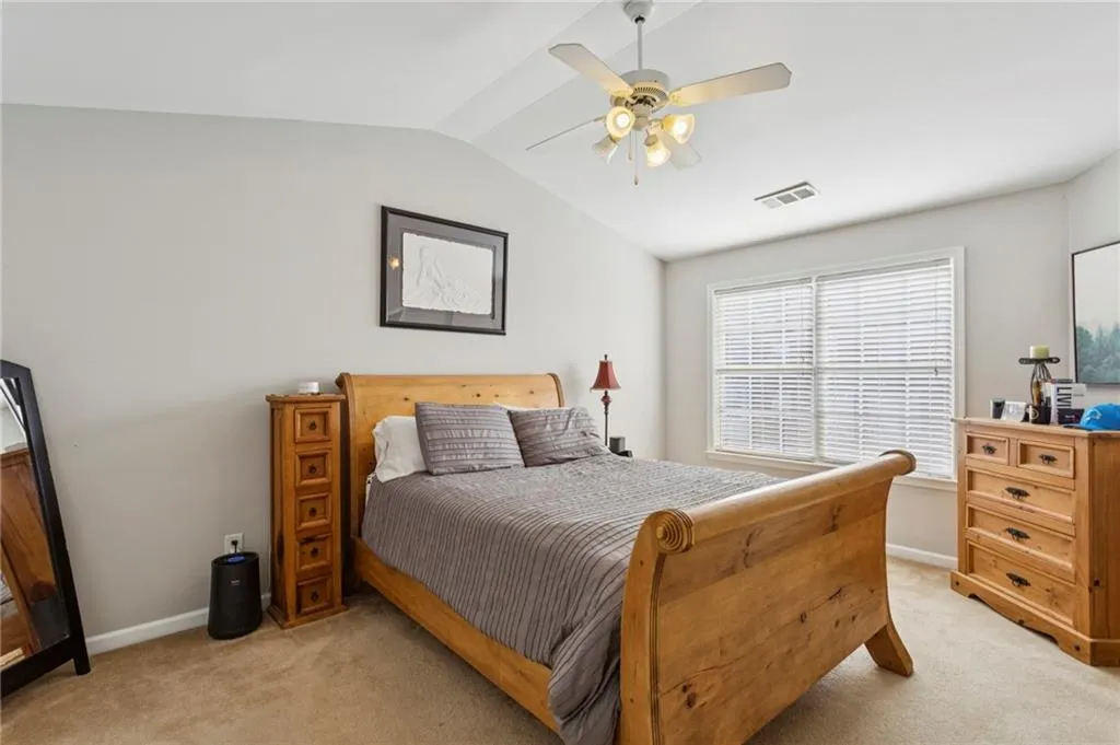 Bedroom with light colored carpet, vaulted ceiling, and great natural light.