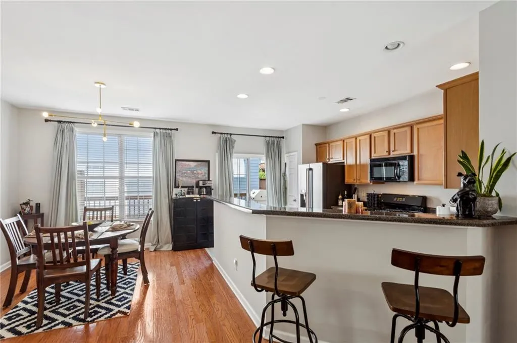 Kitchen featuring a kitchen breakfast bar, light wood-style floors, recessed lighting, black appliances, and dark stone counters