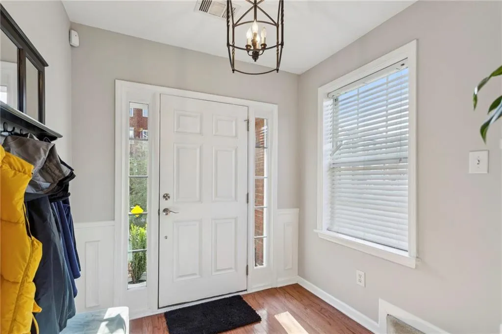 Entrance foyer featuring wood finished floors, a chandelier, and wainscoting
