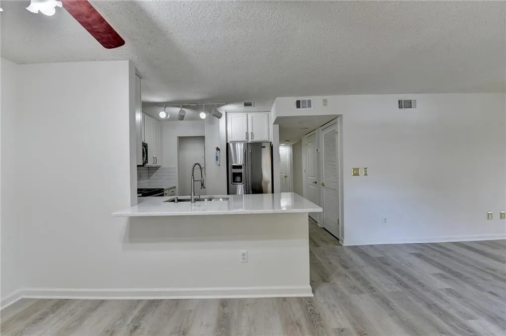 Kitchen featuring high quality fridge, light wood-style flooring, backsplash, white cabinetry, and a textured ceiling