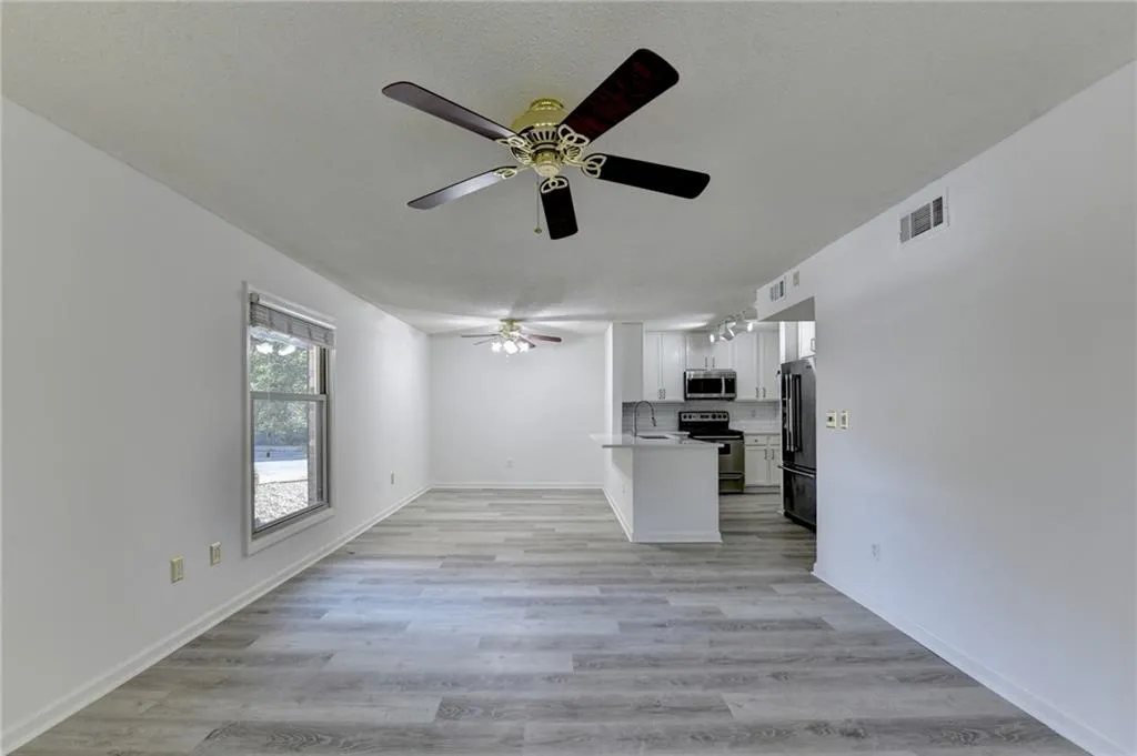 Kitchen with white cabinets, open floor plan, appliances with stainless steel finishes, light wood-style flooring, and a ceiling fan