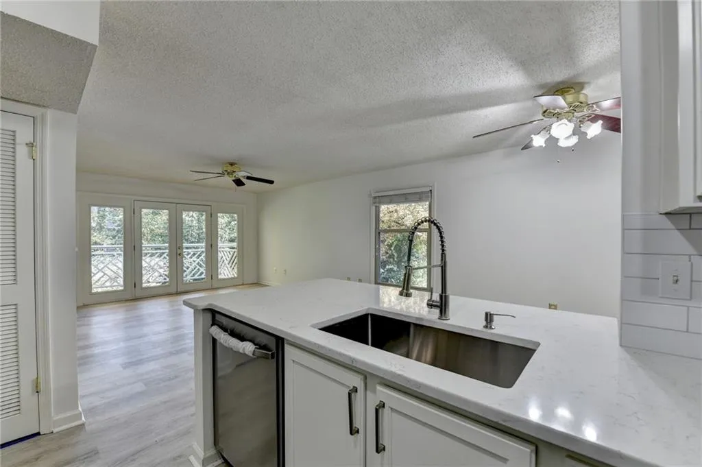 Kitchen with ceiling fan, dishwasher, light stone countertops, a peninsula, and light wood-style flooring