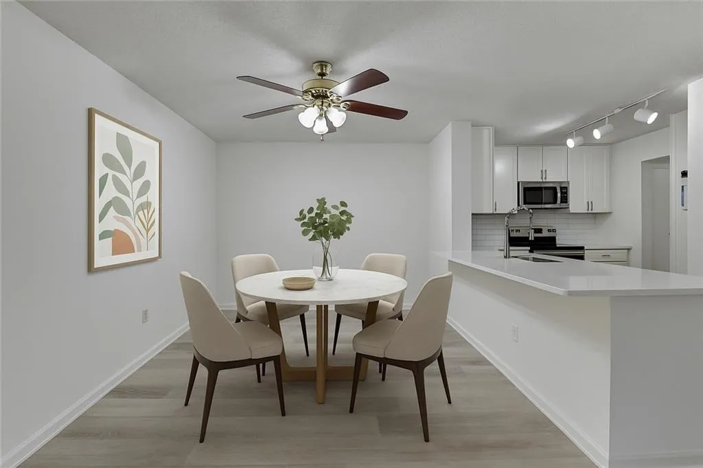 Dining area featuring light wood-style flooring, track lighting, and a ceiling fan