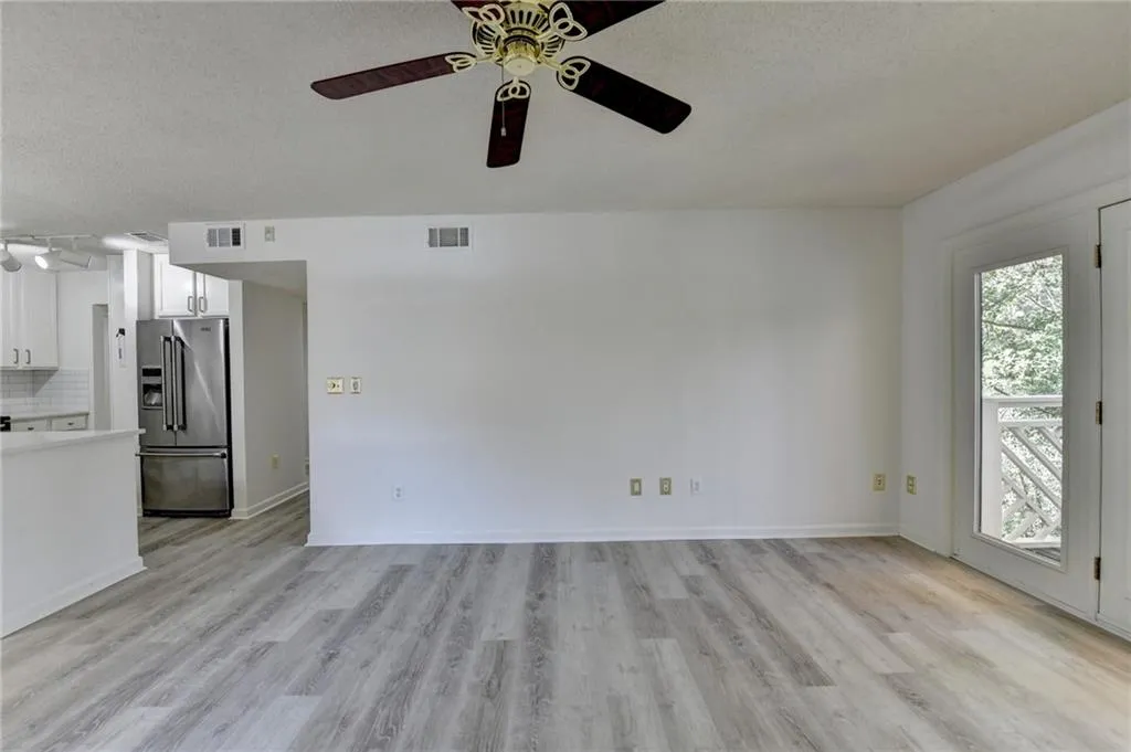 Unfurnished living room featuring light wood finished floors, a textured ceiling, and a ceiling fan