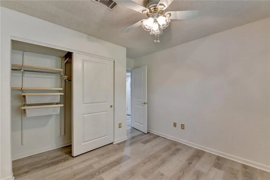 Unfurnished bedroom featuring a closet, a textured ceiling, a ceiling fan, and light wood-type flooring
