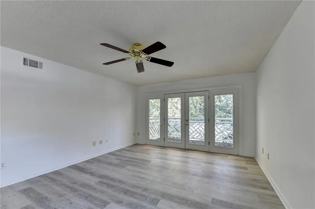 Spare room featuring light wood finished floors, a textured ceiling, a ceiling fan, and french doors