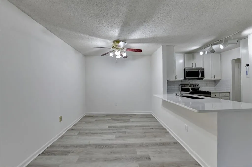 Kitchen featuring decorative backsplash, light wood-style flooring, a peninsula, appliances with stainless steel finishes, and a textured ceiling
