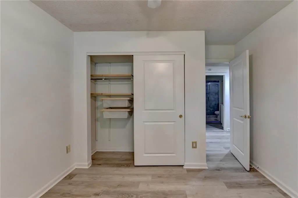 Unfurnished bedroom with light wood-style floors, a textured ceiling, a closet, and a ceiling fan