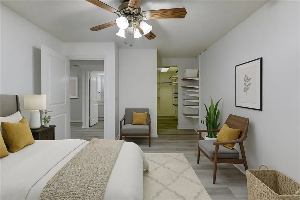Bedroom featuring a walk in closet, light wood finished floors, and ceiling fan