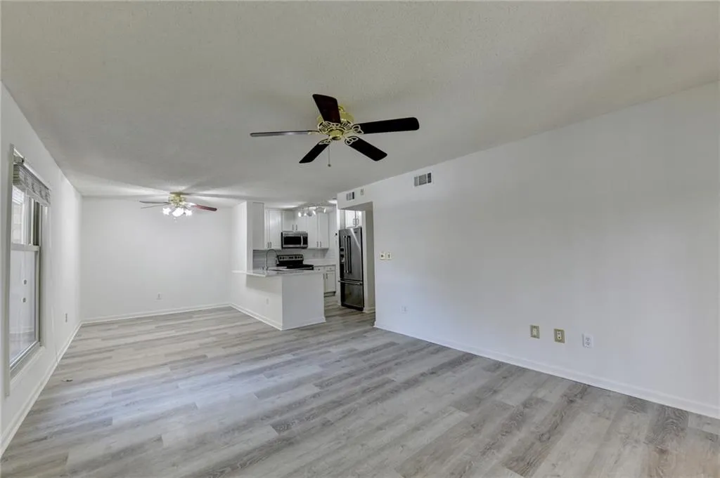 Unfurnished living room with ceiling fan, light wood-style floors, and a textured ceiling