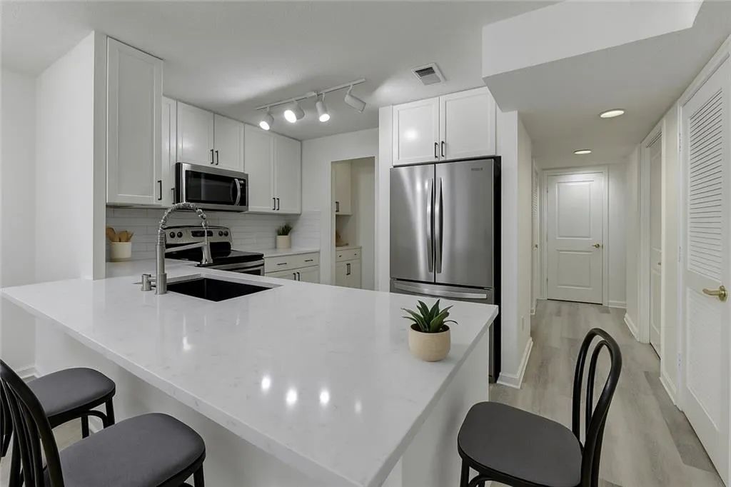 Kitchen featuring a breakfast bar, tasteful backsplash, white cabinetry, a peninsula, and recessed lighting