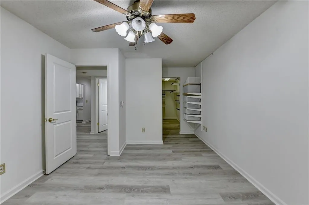 Unfurnished bedroom with light wood-style floors, a textured ceiling, and a ceiling fan