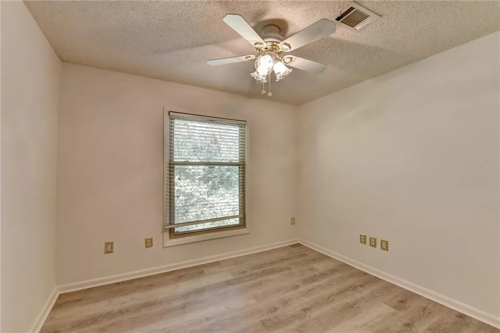Unfurnished room featuring light wood finished floors, a textured ceiling, and ceiling fan