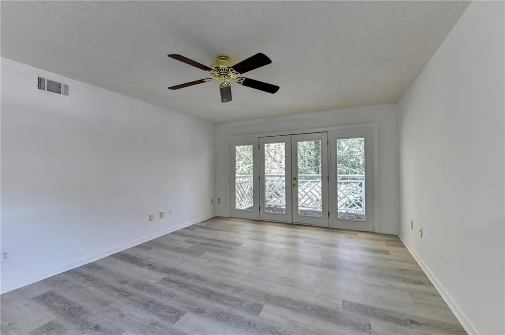 Unfurnished room featuring a textured ceiling, light wood-type flooring, french doors, and ceiling fan