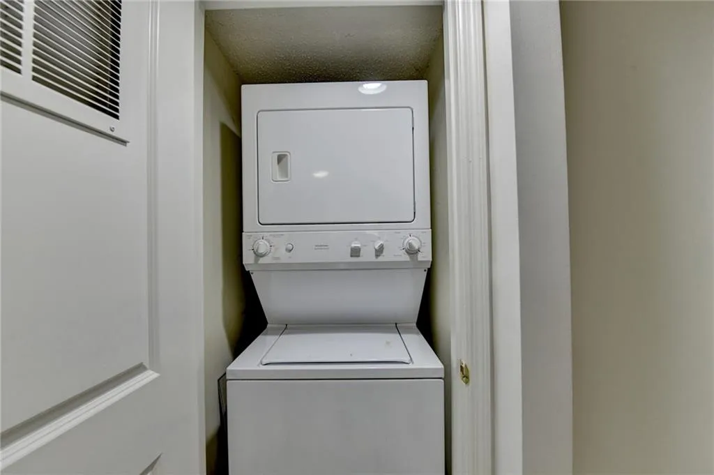 Washroom featuring stacked washer / dryer, a textured ceiling, and a heating unit
