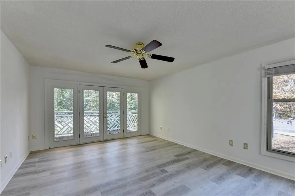 Empty room featuring french doors, light wood-style floors, a textured ceiling, and a ceiling fan