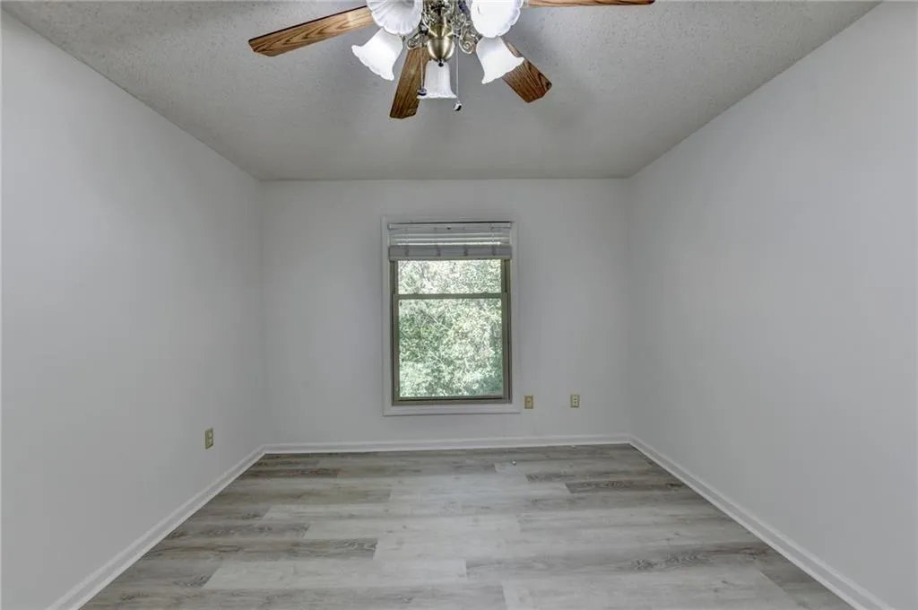 Spare room featuring light wood-style floors, a textured ceiling, and ceiling fan