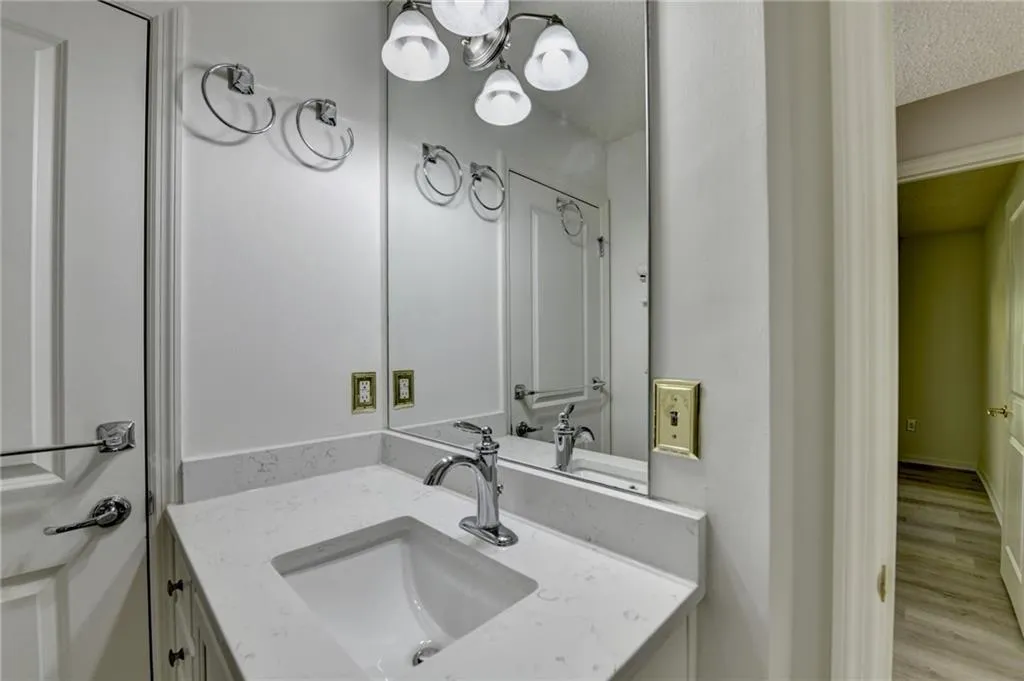 Bathroom with vanity, a chandelier, a textured ceiling, and wood finished floors