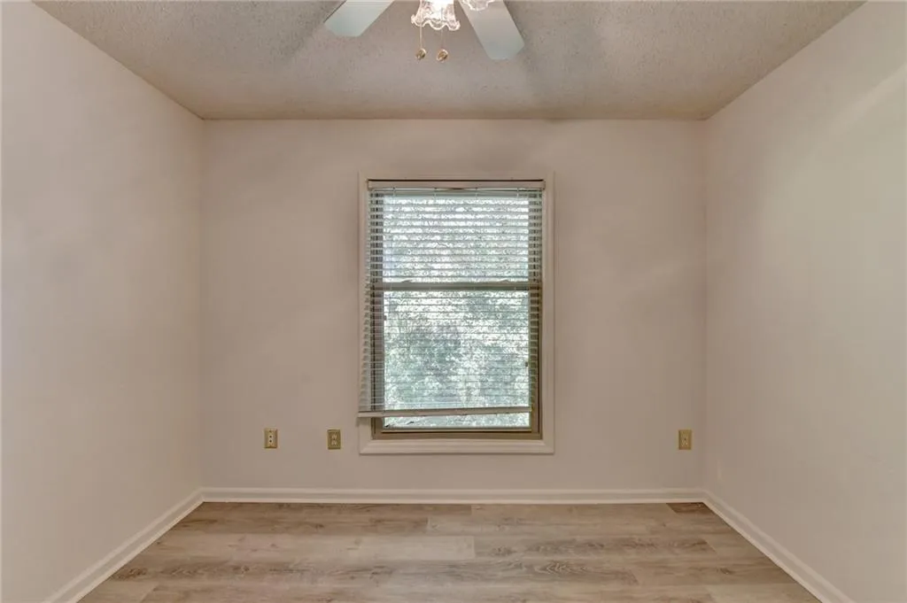 Empty room featuring a textured ceiling, light wood-style floors, and ceiling fan
