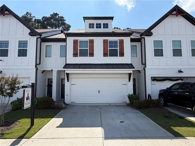 White brick exterior with black trim, wood-toned decorative shutters, and a two-car garage