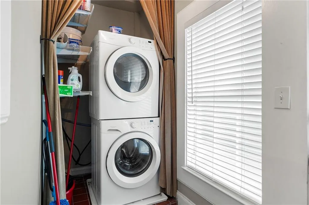 Clothes washing area featuring stacked washer / drying machine and baseboards