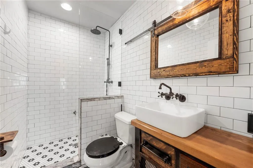 Bathroom with a tile shower, tile walls, toilet, and vanity