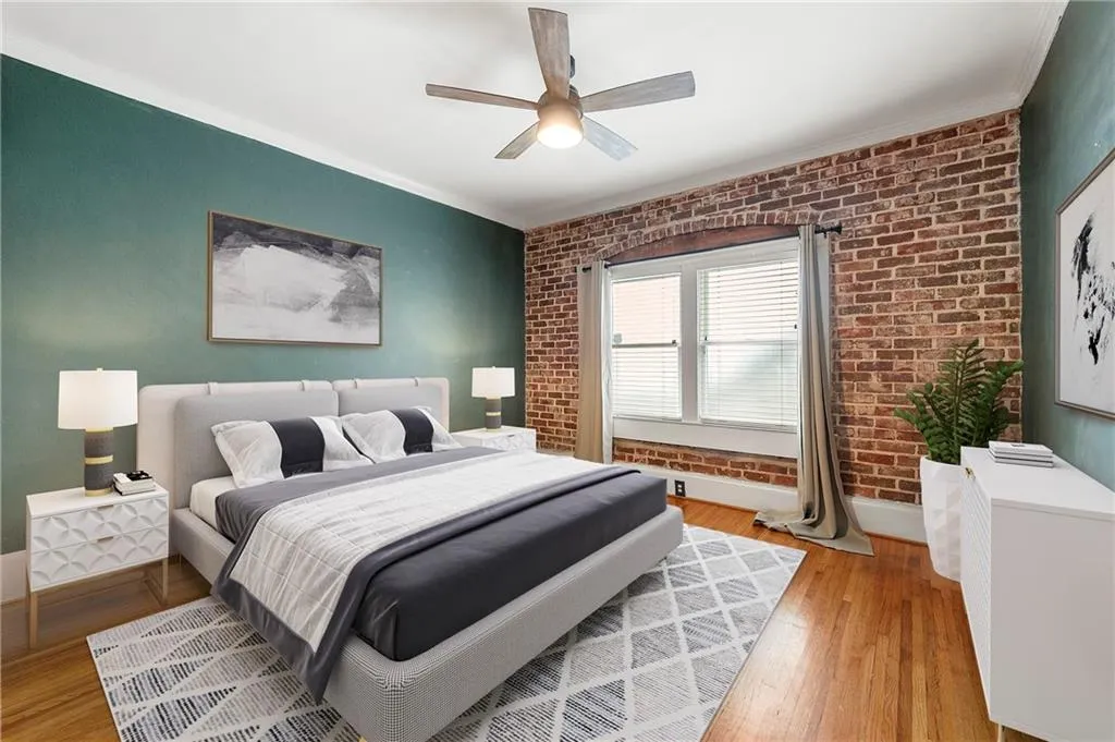 Bedroom featuring brick wall, light wood-type flooring, crown molding, ceiling fan, and baseboards