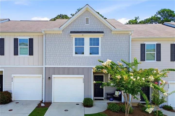Townhome exterior featuring light gray shake siding, vertical paneling, and a prominent gable