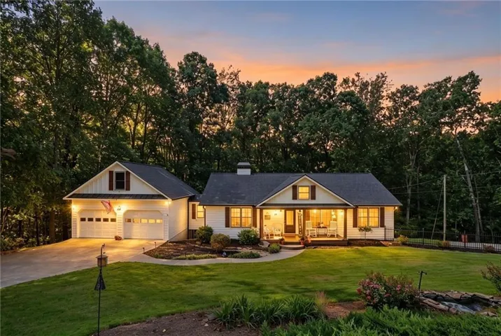 White siding residence with a two-car garage, covered front porch, and manicured lawn