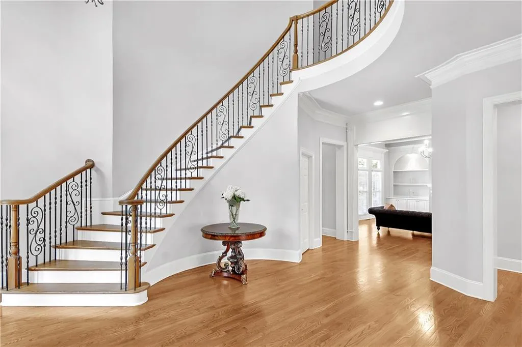Stairway featuring crown molding, a towering ceiling, and light wood-type flooring