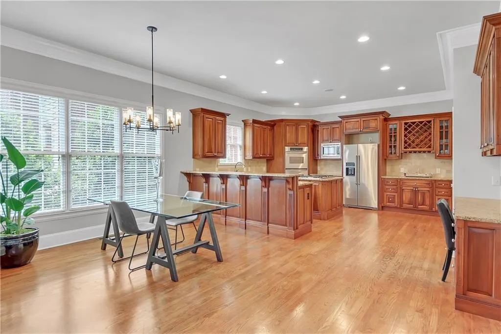 Kitchen with crown molding, stainless steel appliances, light wood-type flooring, backsplash, and hanging light fixtures