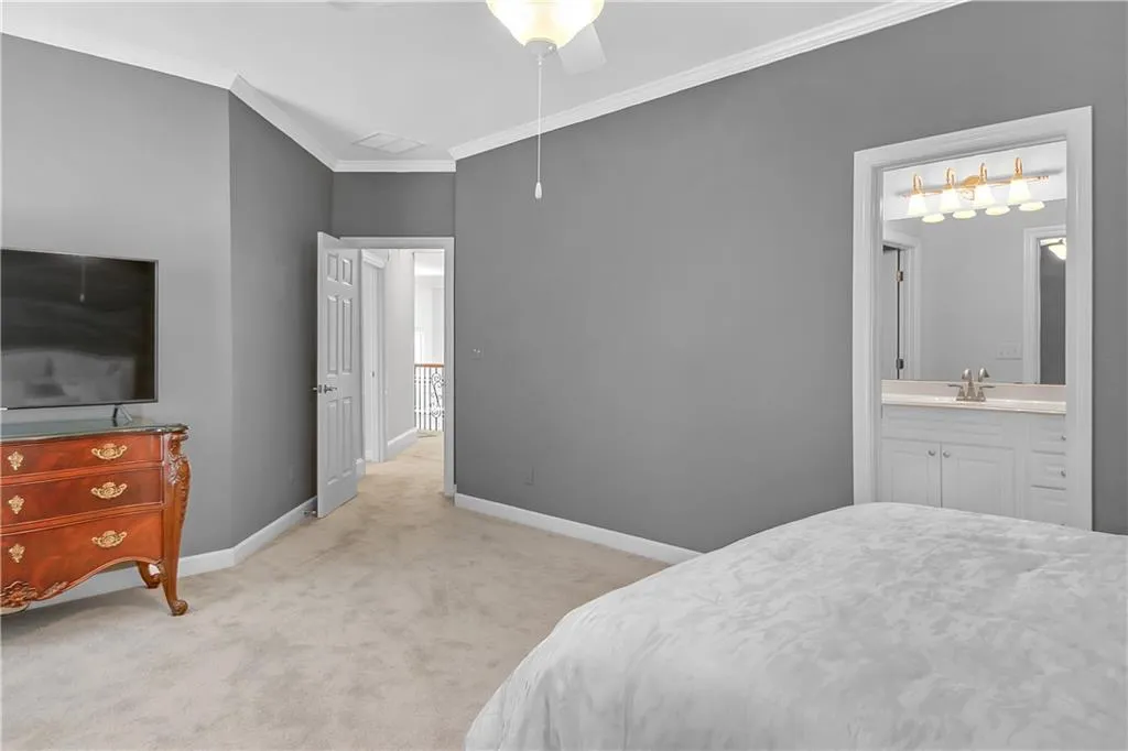 Carpeted bedroom featuring ensuite bathroom, ceiling fan, crown molding, and sink