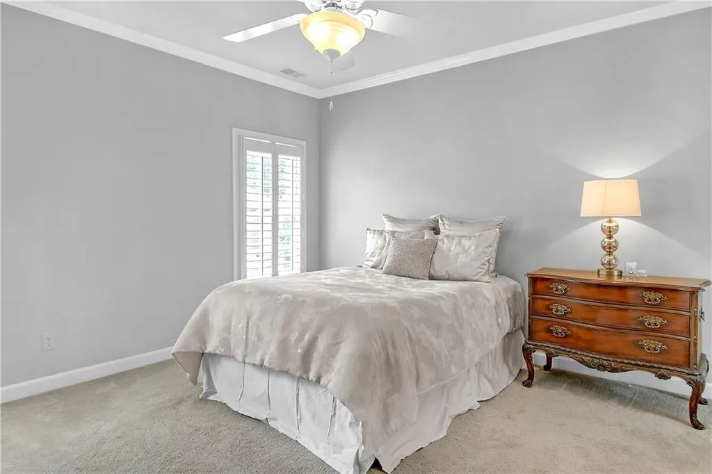 Carpeted bedroom with ceiling fan and ornamental molding